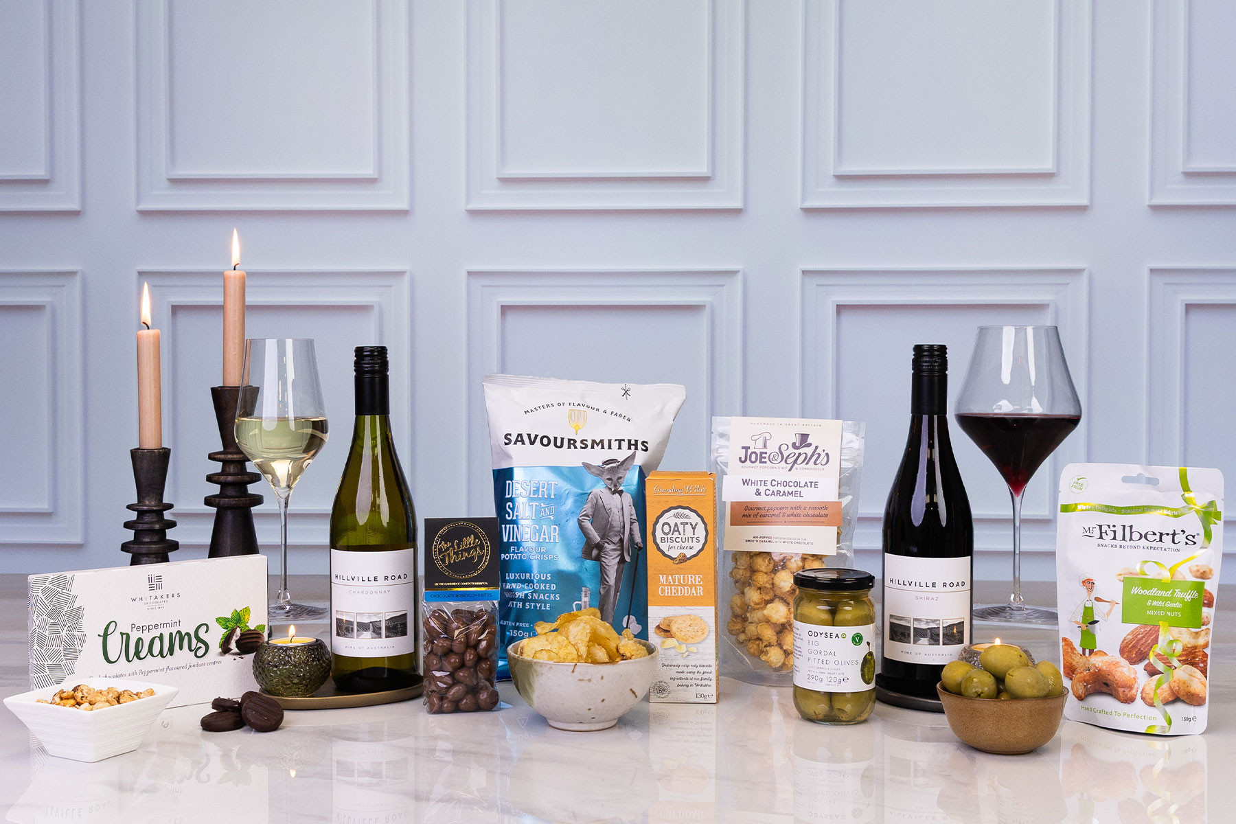 Luxury food and wine gift hamper featuring Chardonnay and Shiraz, gourmet crisps, popcorn, chocolates, olives, mixed nuts, biscuits and candles.
