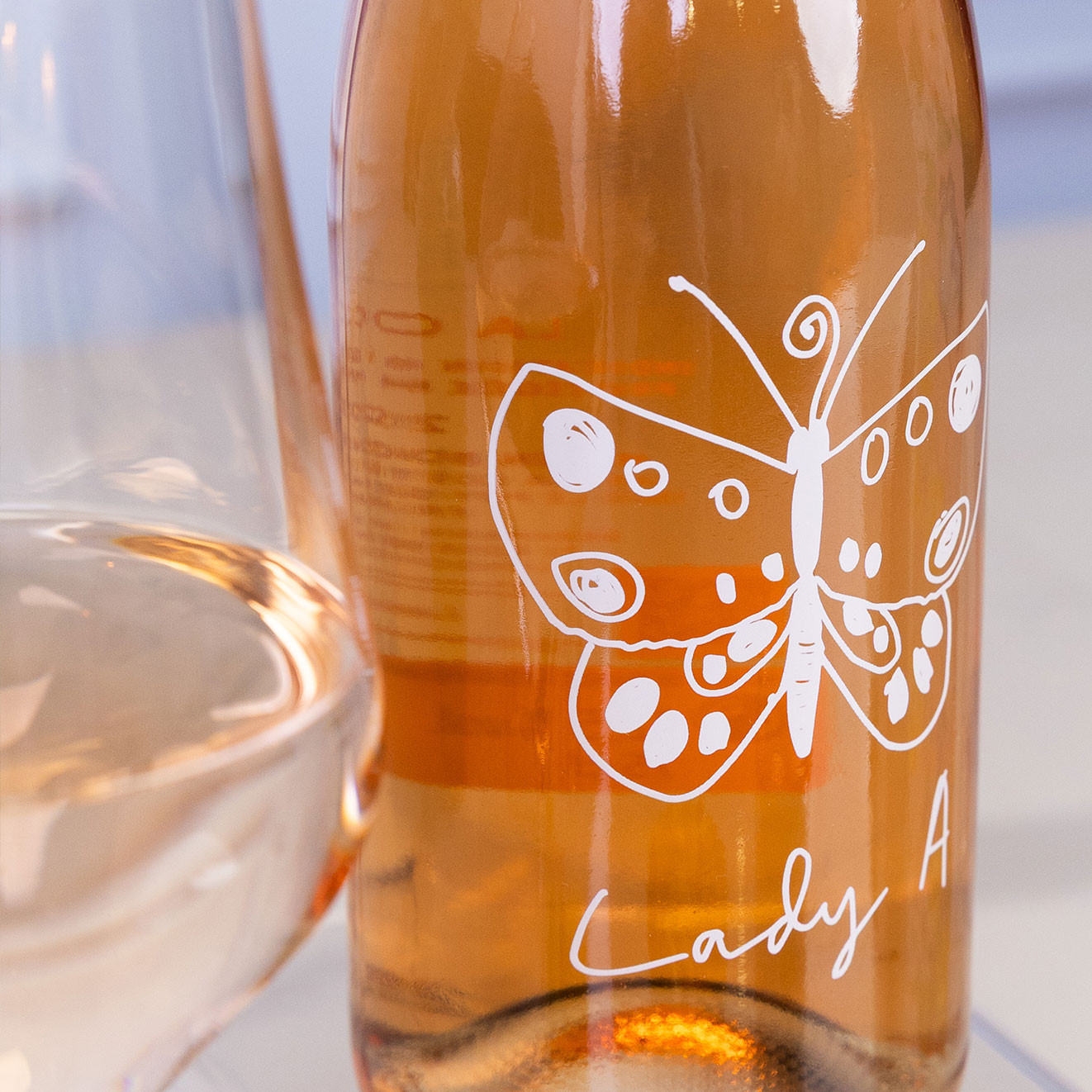 Bottle of Lady A rosé wine with a butterfly design displayed beside a glass of rosé wine.