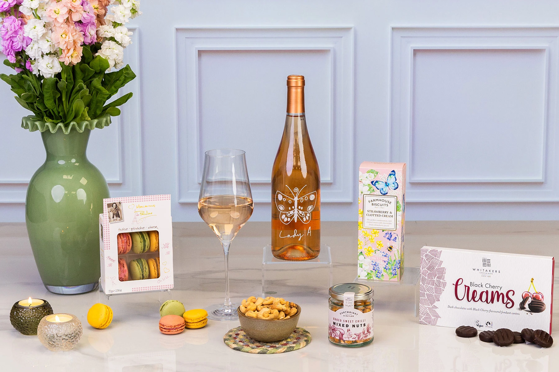  Luxury rosé wine gift hamper featuring Lady A rosé, French macarons, strawberry and clotted cream biscuits, black cherry creams, sweet chilli mixed nuts, candles and fresh flowers.