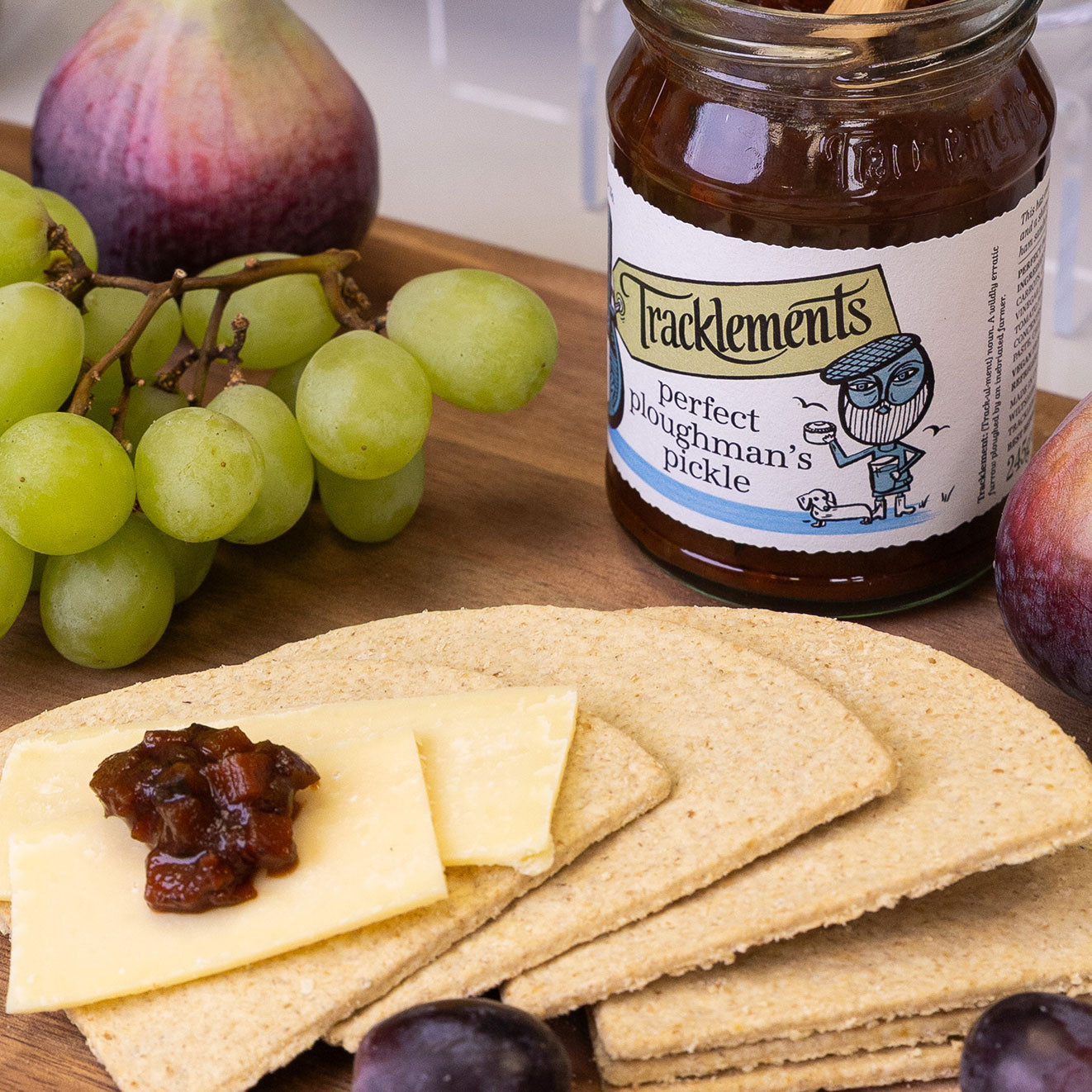 Crackers topped with cheese and ploughman's pickle served with grapes and a jar of Tracklements Perfect Ploughman's Pickle.