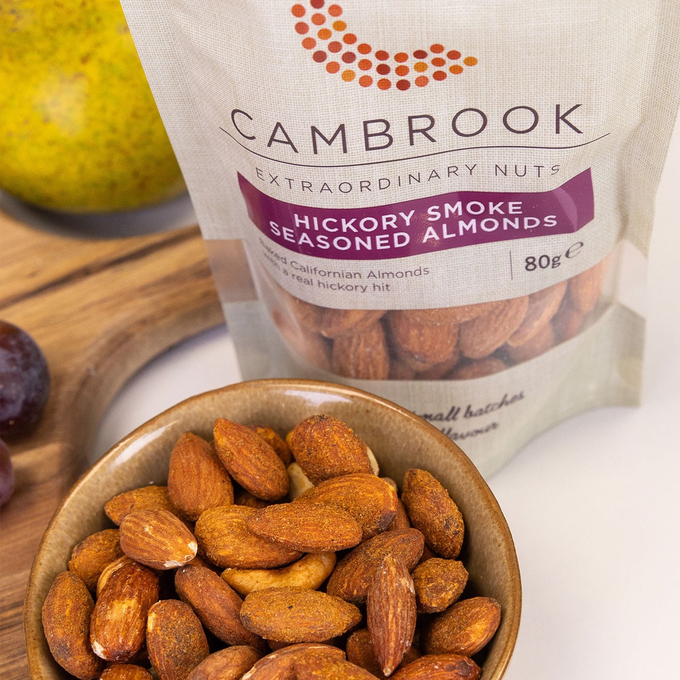 Cambrook Hickory Smoke Seasoned Almonds displayed in a bowl beside the resealable pack.
