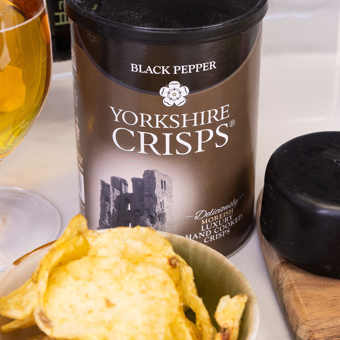 Yorkshire Crisps Black Pepper hand cooked crisps displayed beside a bowl of black pepper crisps.