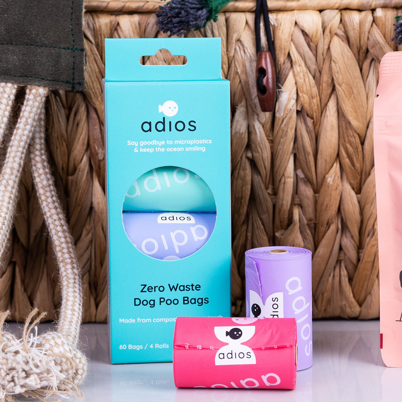 Box of Adios Zero Waste Dog Poo Bags with two colourful compostable bag rolls displayed in front.
