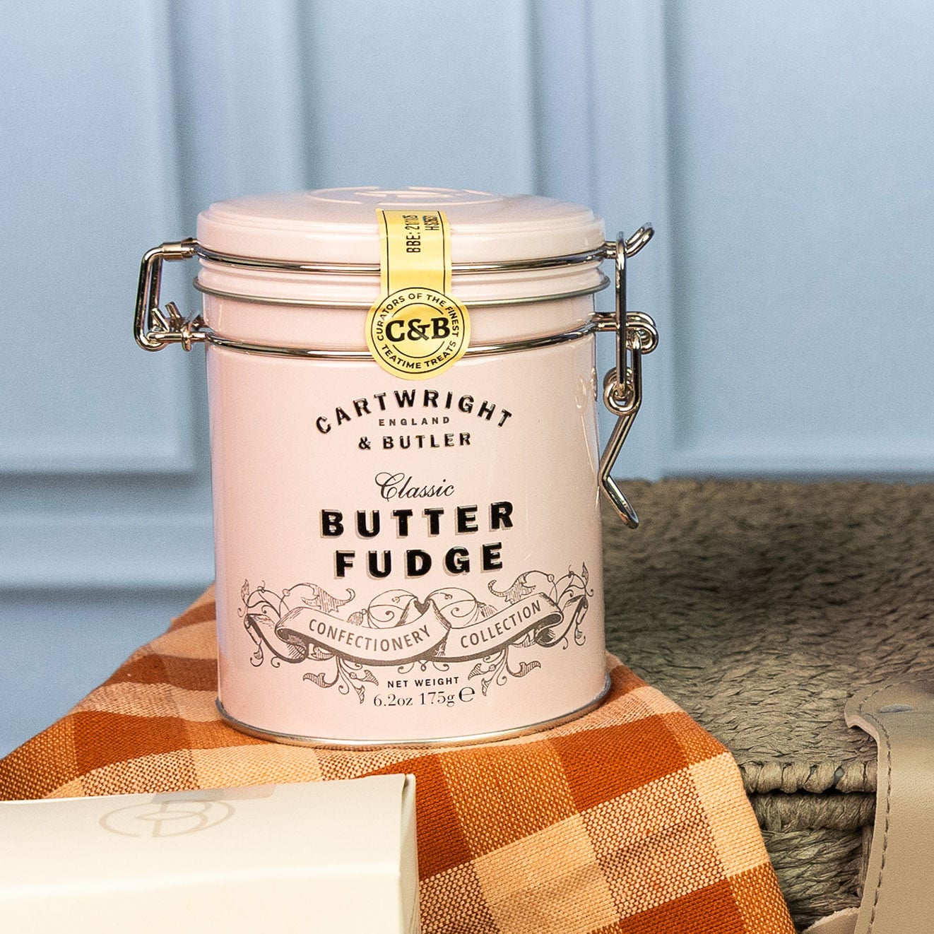 Cartwright & Butler Classic Butter Fudge presented in a reusable clip-top tin displayed on a rope hamper.