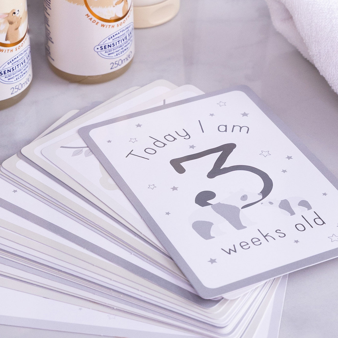 Baby milestone cards from The Little White Company featuring a Today I am 3 weeks old design with soft grey illustrations.