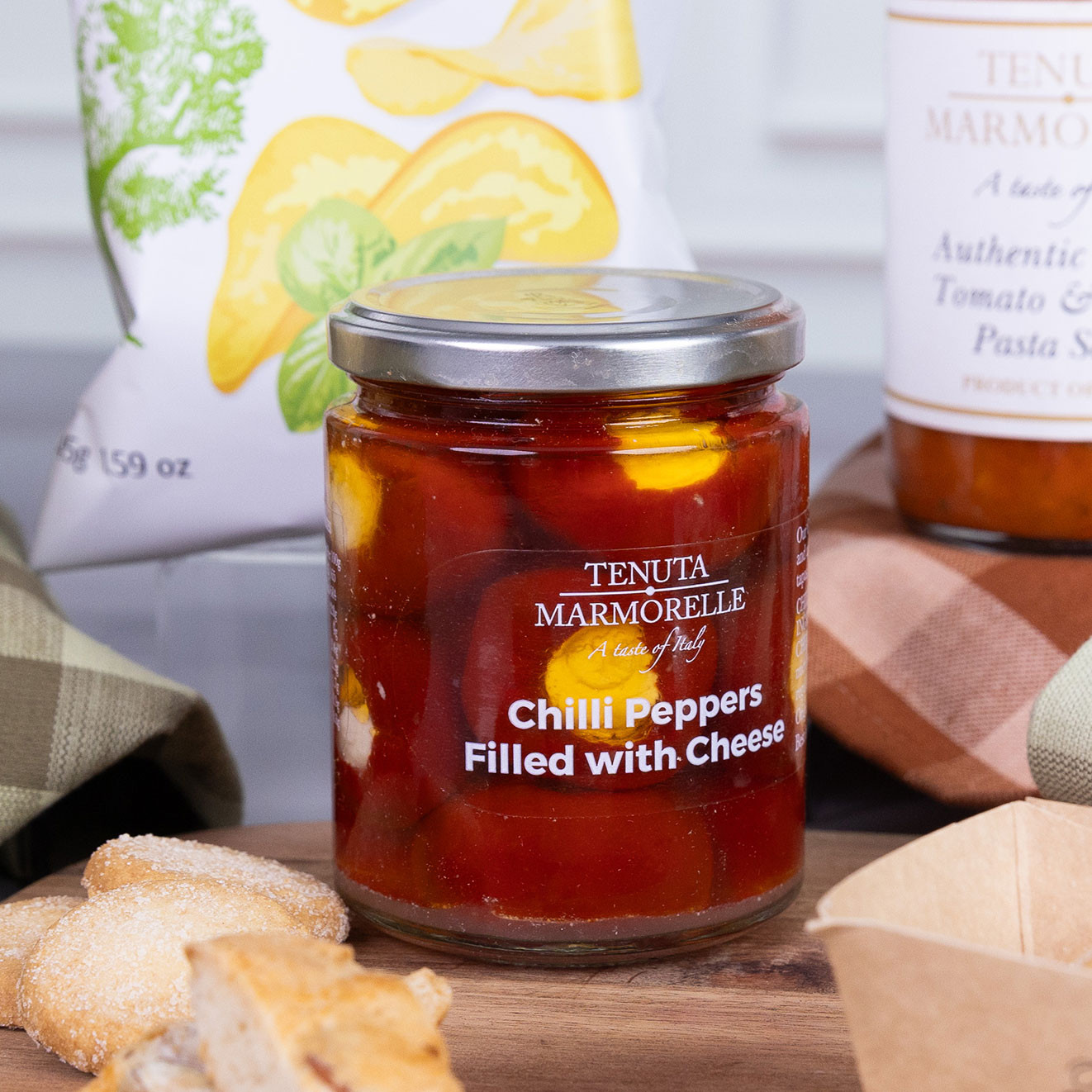 Jar of Tenuta Marmorelle Chilli Peppers Filled with Cheese presented with artisan bread, pesto chips and authentic Italian pasta sauce.