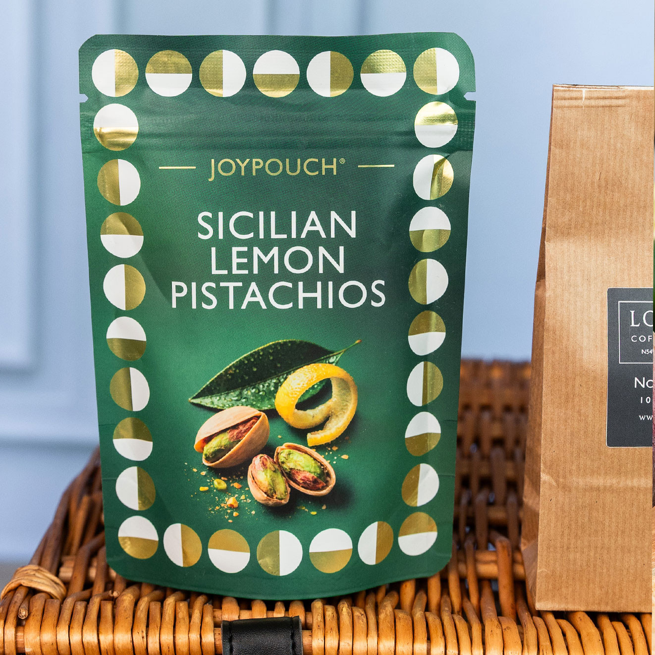 JoyPouch Sicilian Lemon Pistachios in a premium gift pouch displayed on the luxury wicker hamper.