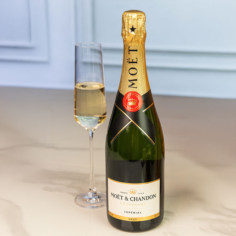 Bottle of Moët & Chandon Impérial Brut Champagne served alongside a filled champagne flute on a marble surface.
