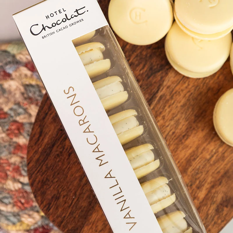 Hotel Chocolat Vanilla Macarons presented in a gift box with delicate vanilla macarons arranged on a wooden serving board.