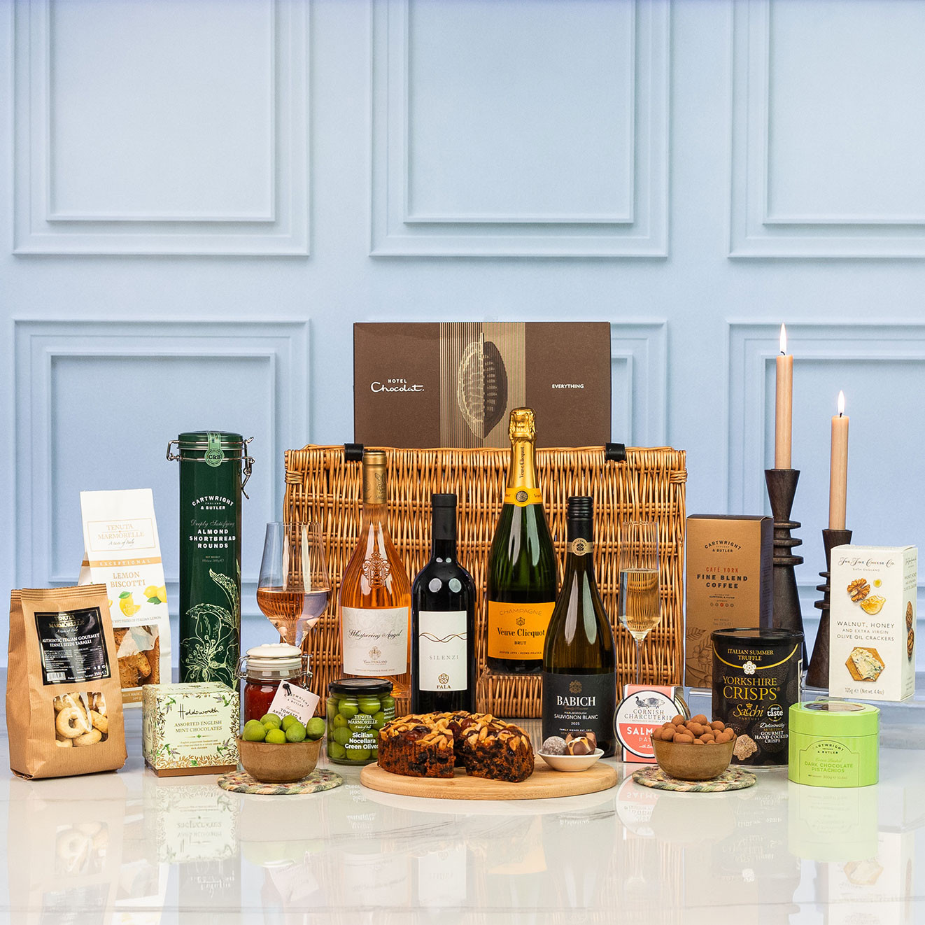 Square shot of the Luxury wicker hamper featuring Veuve Clicquot Champagne, Whispering Angel rosé, red and white wines, artisan sweet and savoury treats, fruit cake, chocolates and gourmet snacks.