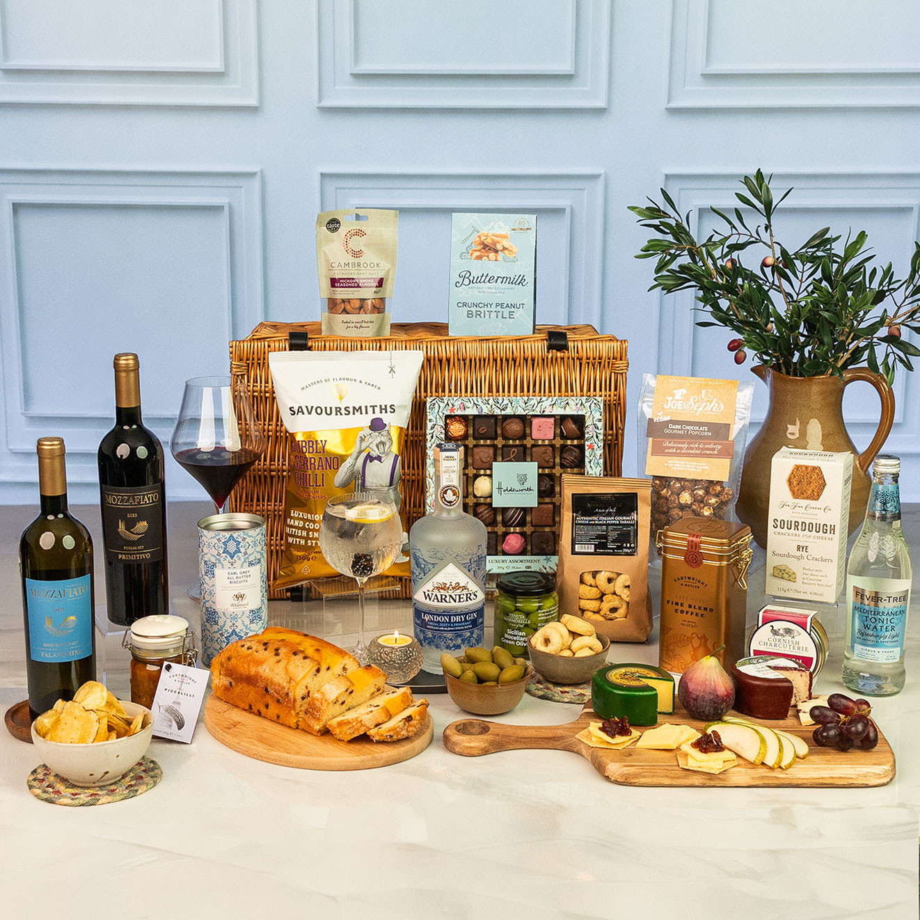 Square shot of the luxury wicker hamper featuring Italian wines, Warner's London Dry Gin, artisan chocolates, gourmet snacks, cheeses, pâté, olives, tonic water and sweet treats.