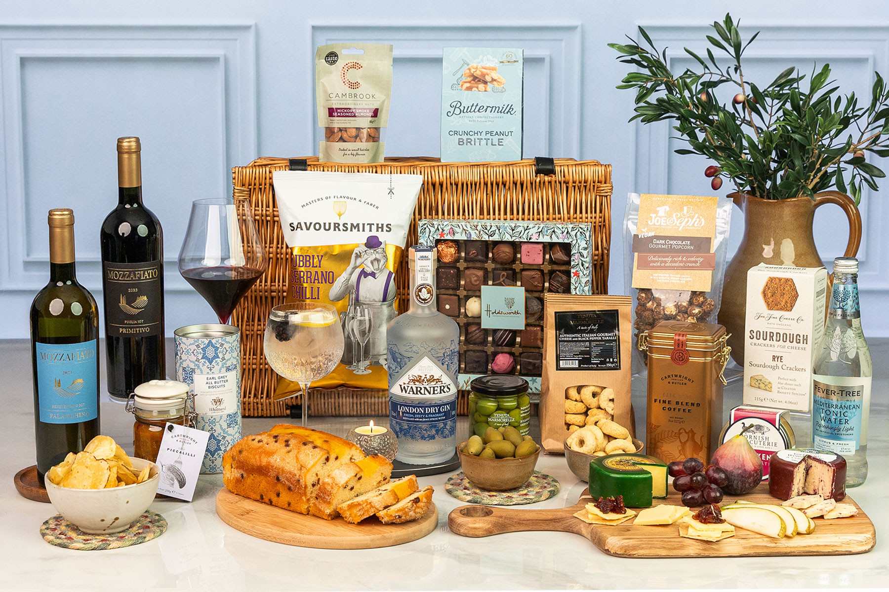 Luxury wicker hamper featuring Italian wines, Warner's London Dry Gin, artisan chocolates, gourmet snacks, cheeses, pâté, olives, tonic water and sweet treats.
