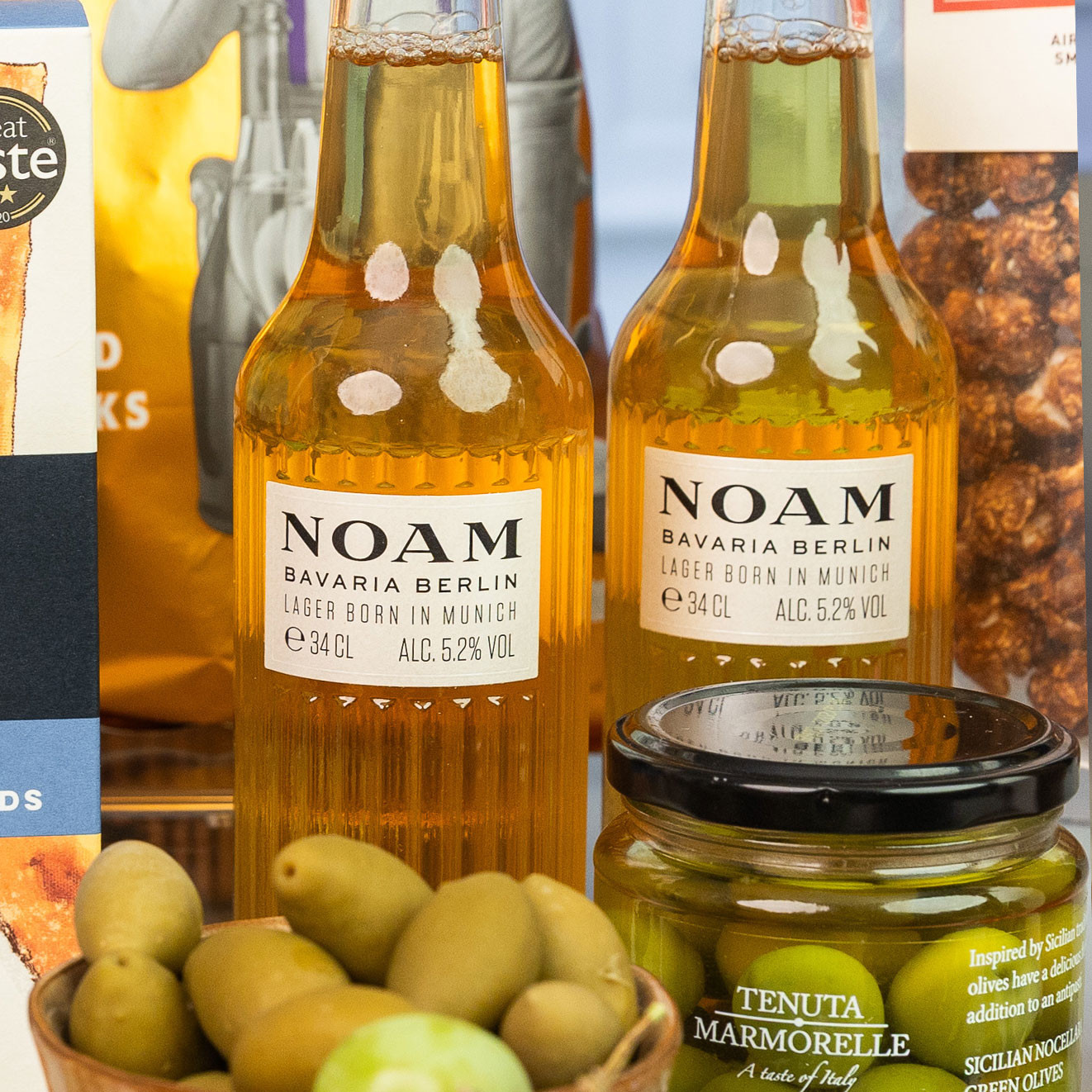 Two bottles of NOAM Bavarian Berlin lager served with Sicilian Nocellara green olives for a gourmet aperitif.