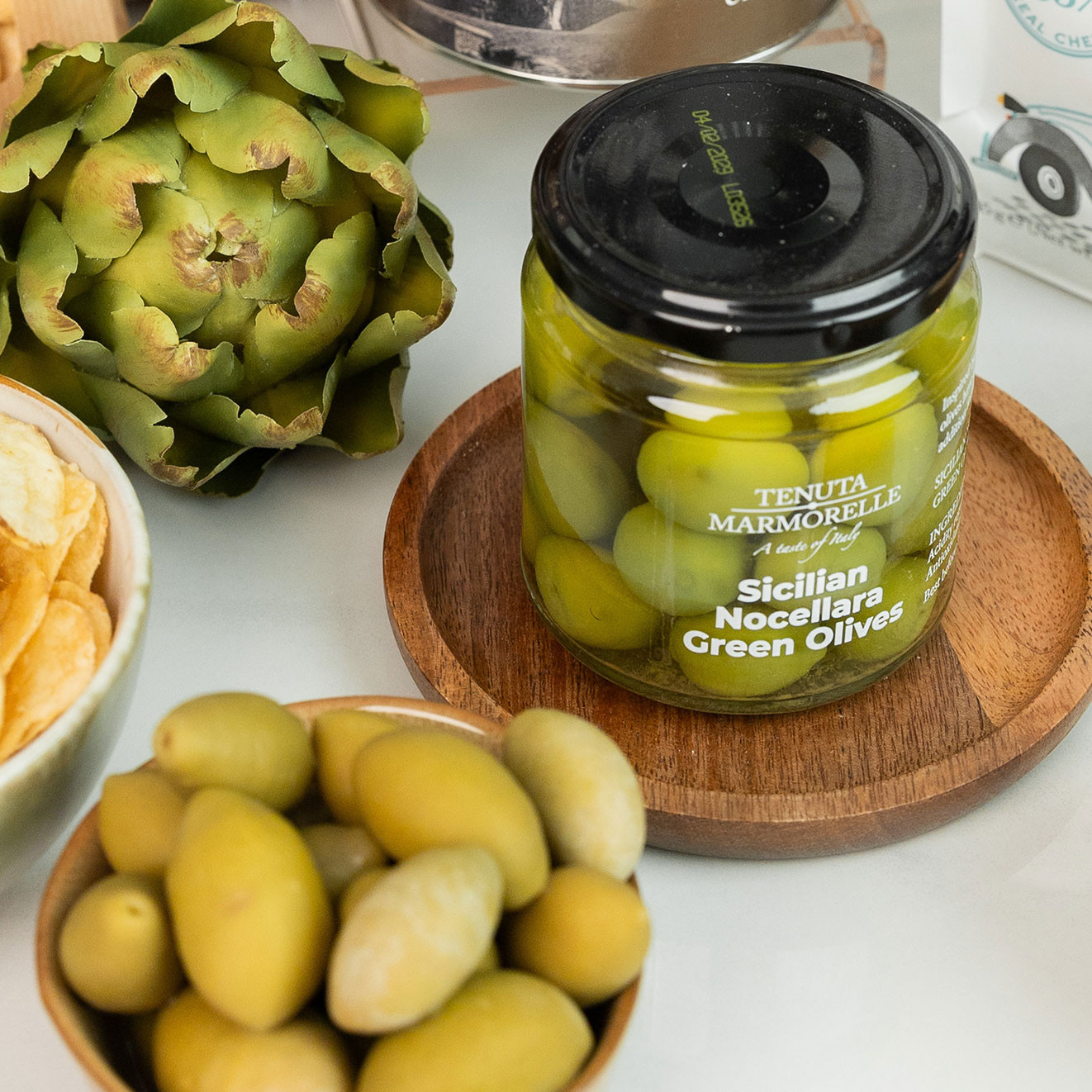Tenuta Marmorelle Sicilian Nocellara Green Olives served with crisps and fresh artichoke, perfect for Mediterranean-style entertaining.