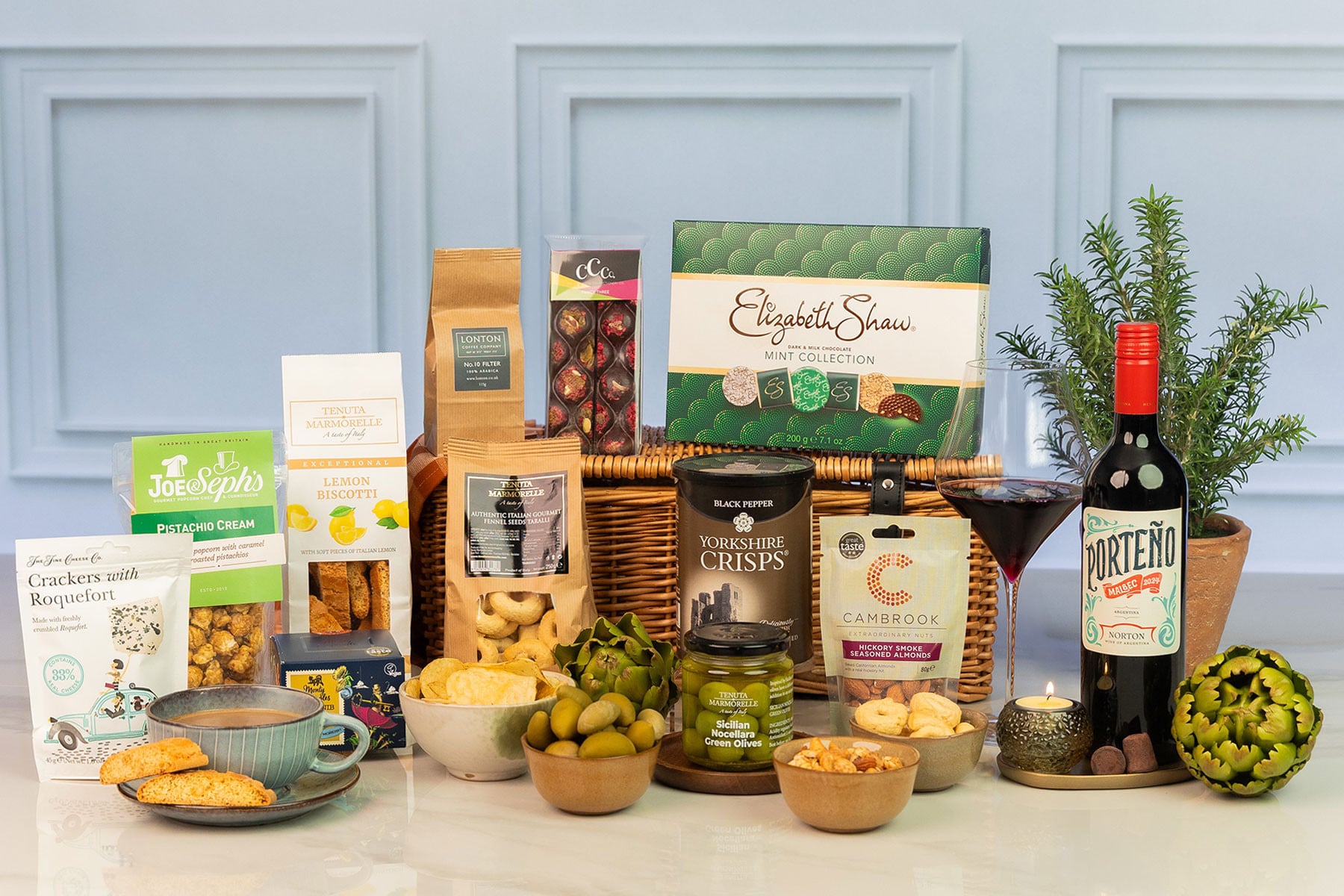 Luxury wicker hamper filled with premium sweet and savoury treats, gourmet snacks, artisan chocolates, coffee, red wine and antipasti for indulgent gifting.