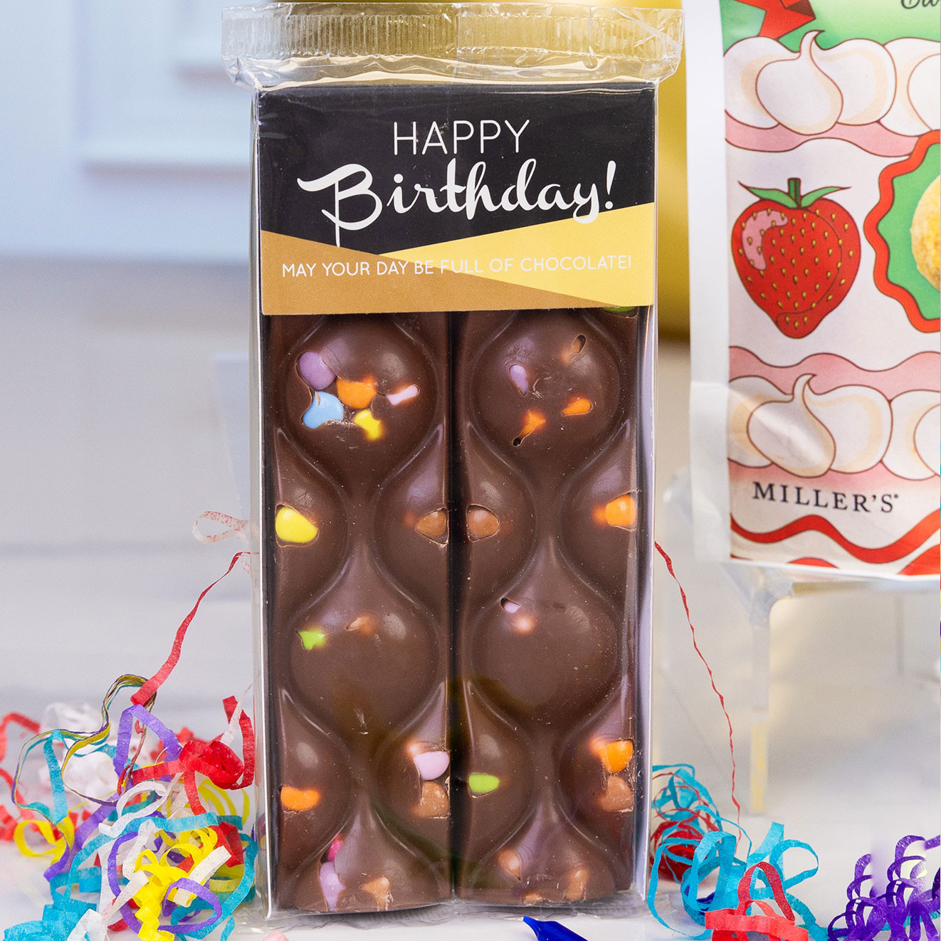 Happy Birthday milk chocolate bar decorated with colourful candy pieces, presented with festive confetti for a fun birthday gift.