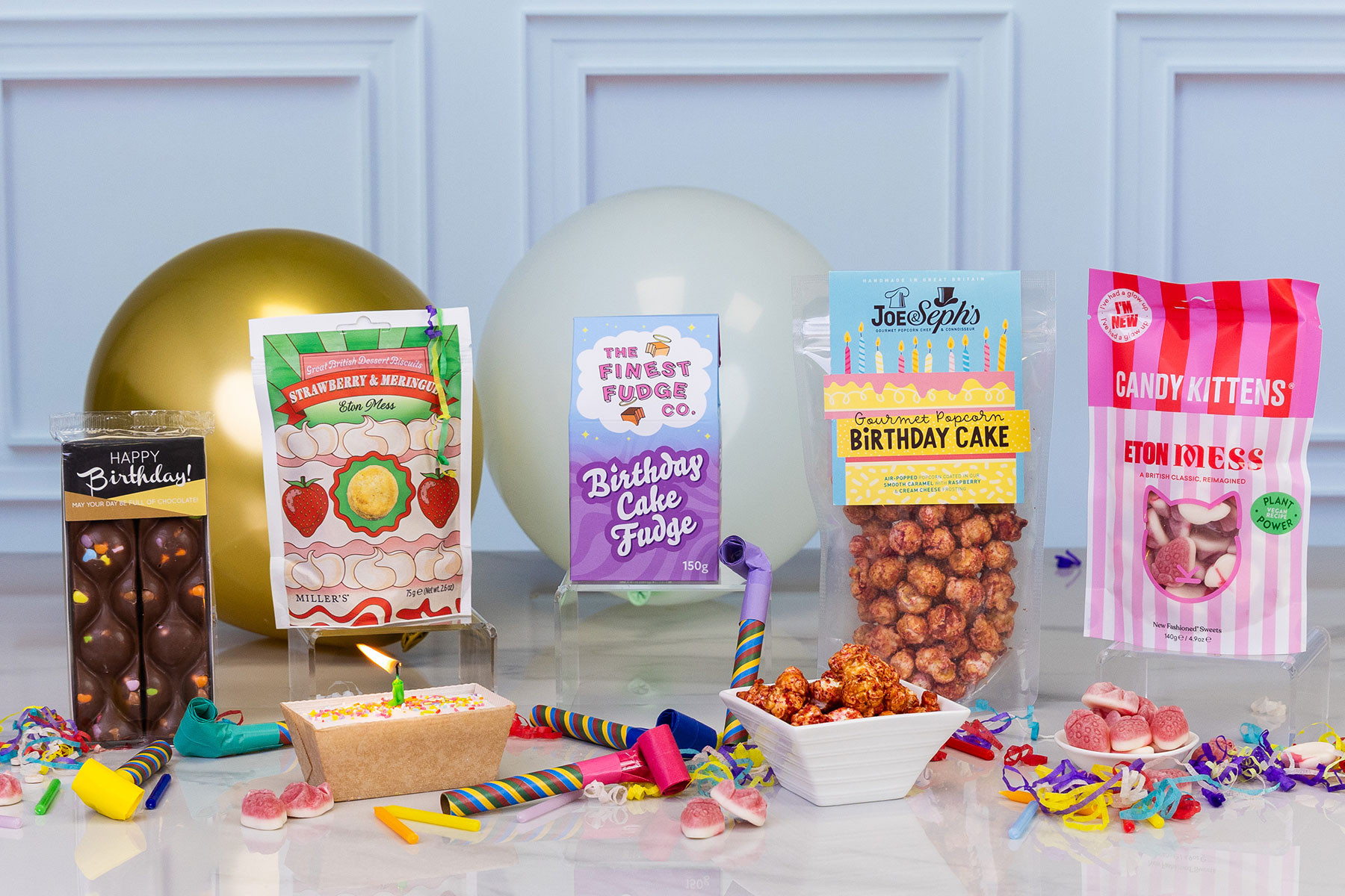 Birthday gift hamper featuring birthday cake fudge, birthday cake popcorn, chocolate bar, Eton Mess sweets, strawberry and meringue biscuits, birthday loaf cake and colourful party decorations.