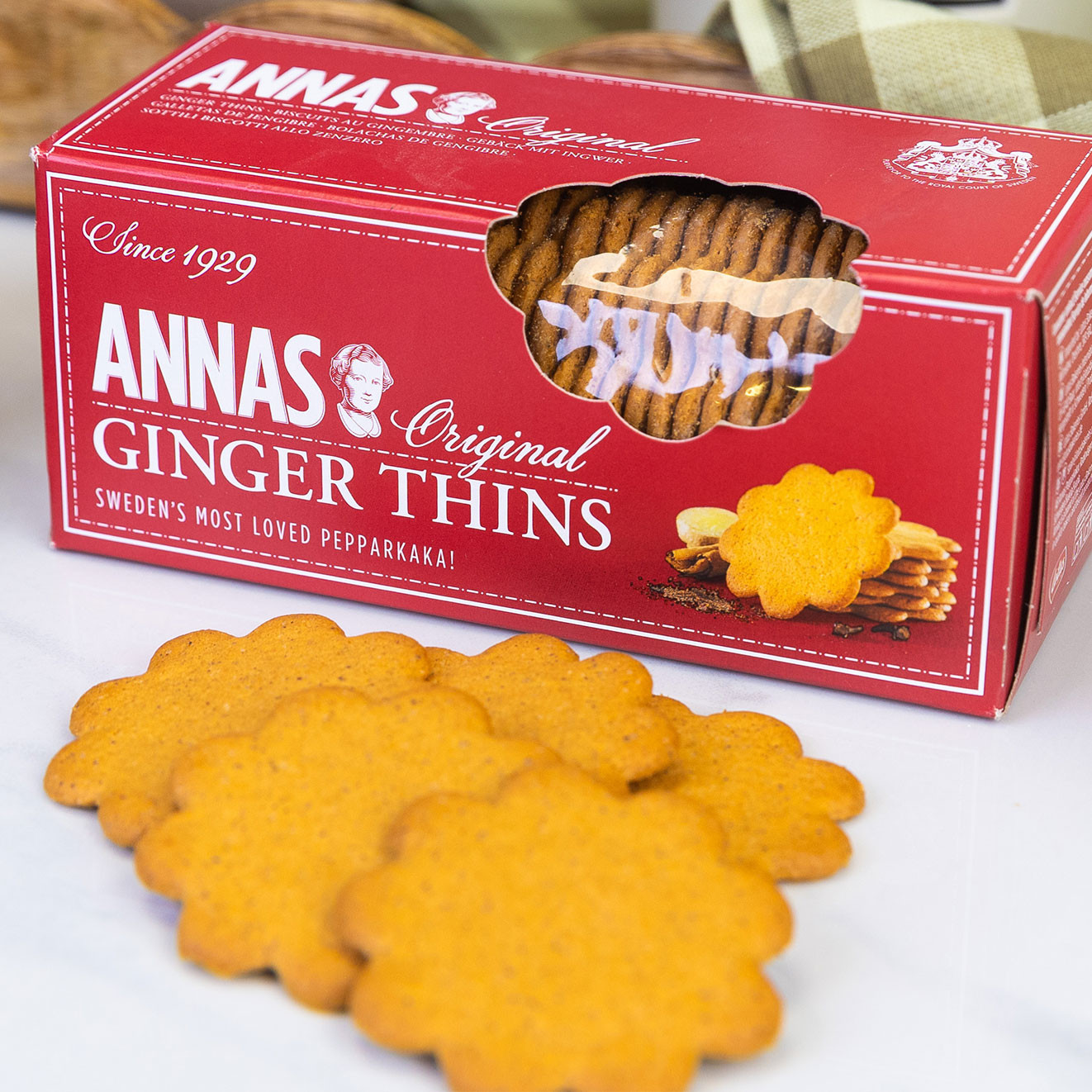 Anna's Original Ginger Thins biscuits in their red box with crisp ginger biscuits arranged in front for serving.