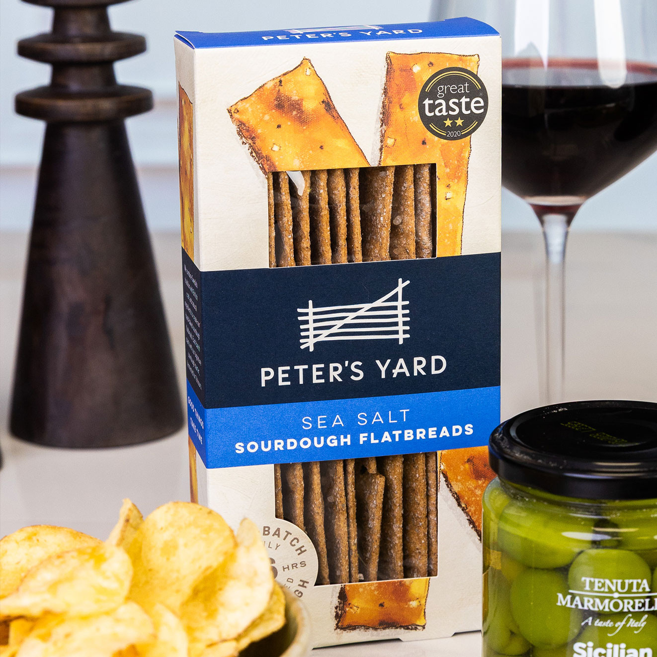 Peter's Yard sea salt sourdough flatbreads displayed with Sicilian green olives, crisps and a glass of red wine for sharing.