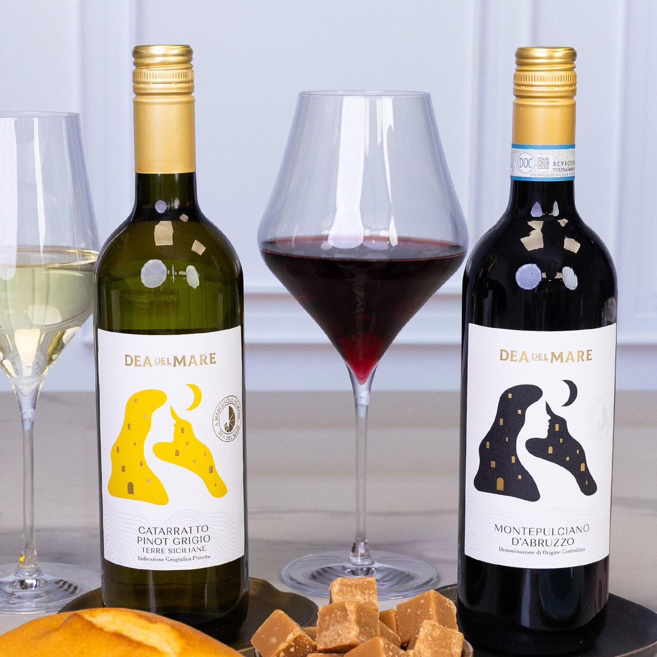 Bottles of Dea del Mare Catarratto Pinot Grigio and Montepulciano d'Abruzzo served alongside glasses of white and red wine.