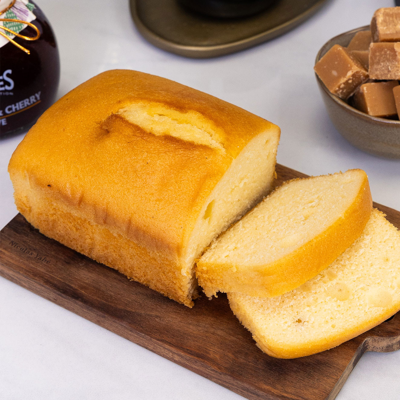 Golden sliced Madeira-style loaf cake displayed on a wooden serving board, ready to enjoy with tea or coffee.