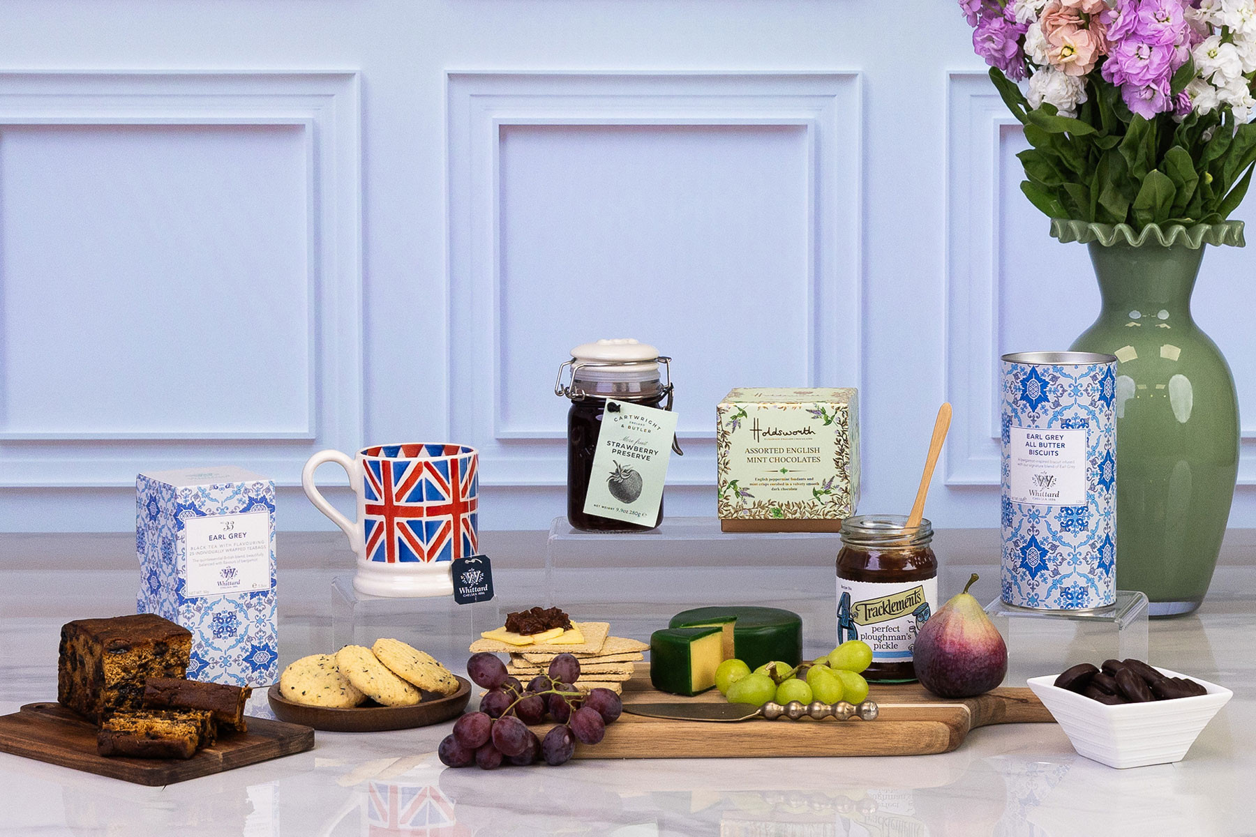 Traditional British afternoon tea gift hamper featuring Earl Grey tea, fruit cake, mint chocolates, artisan biscuits, vintage cheddar, preserves, crackers, fresh fruit and a Union Jack mug.