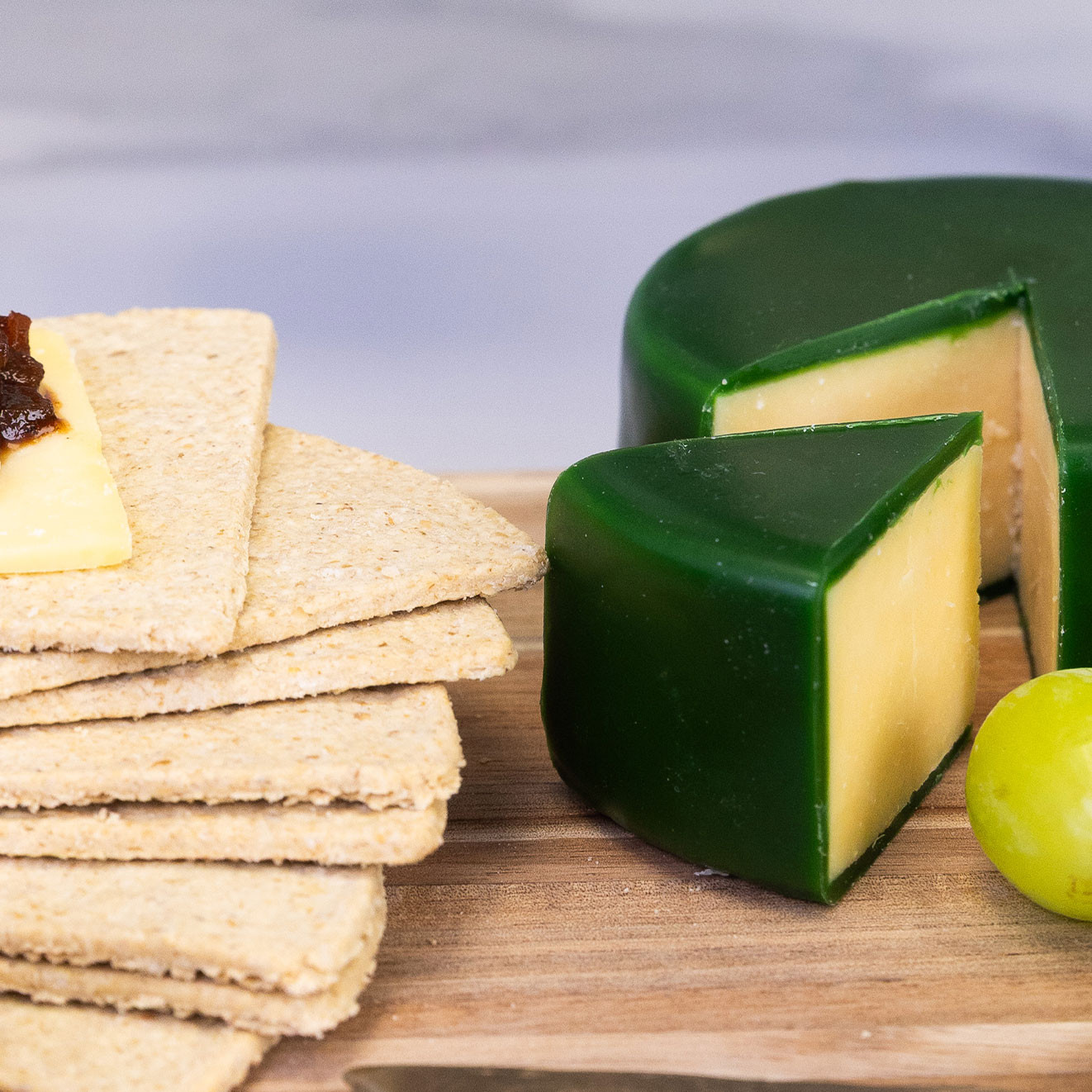 Traditional British vintage cheddar served with crisp crackers and ploughman's pickle, accompanied by fresh grapes for a classic cheeseboard.