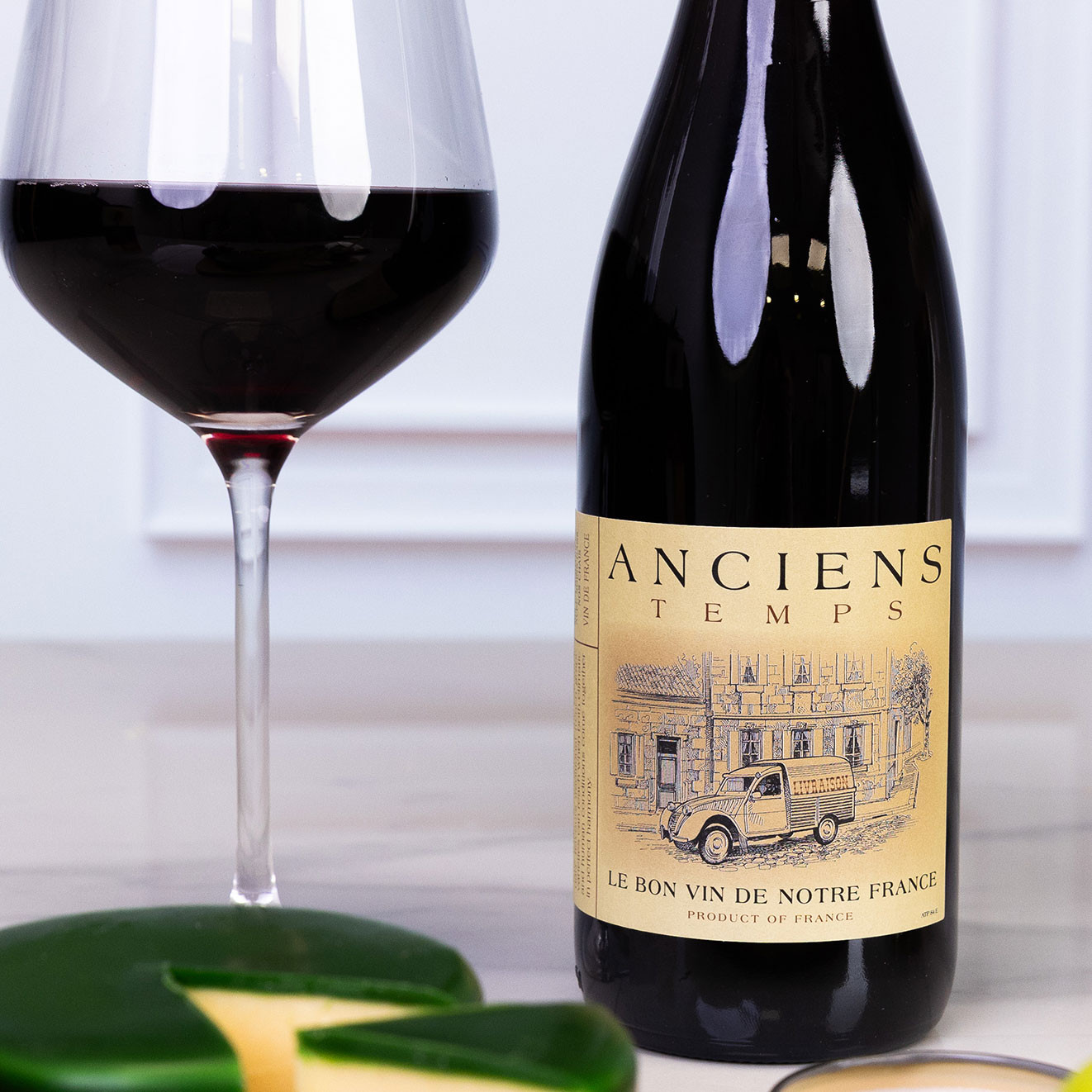 Bottle of Anciens Temps French red wine served alongside a glass of red wine, ideal for cheese boards and relaxed evenings.
