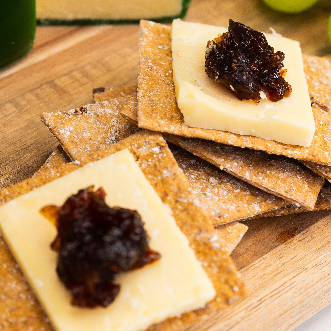 Fig and spelt sourdough crackers topped with slices of mature cheese and caramelised onion marmalade for a classic savoury bite.