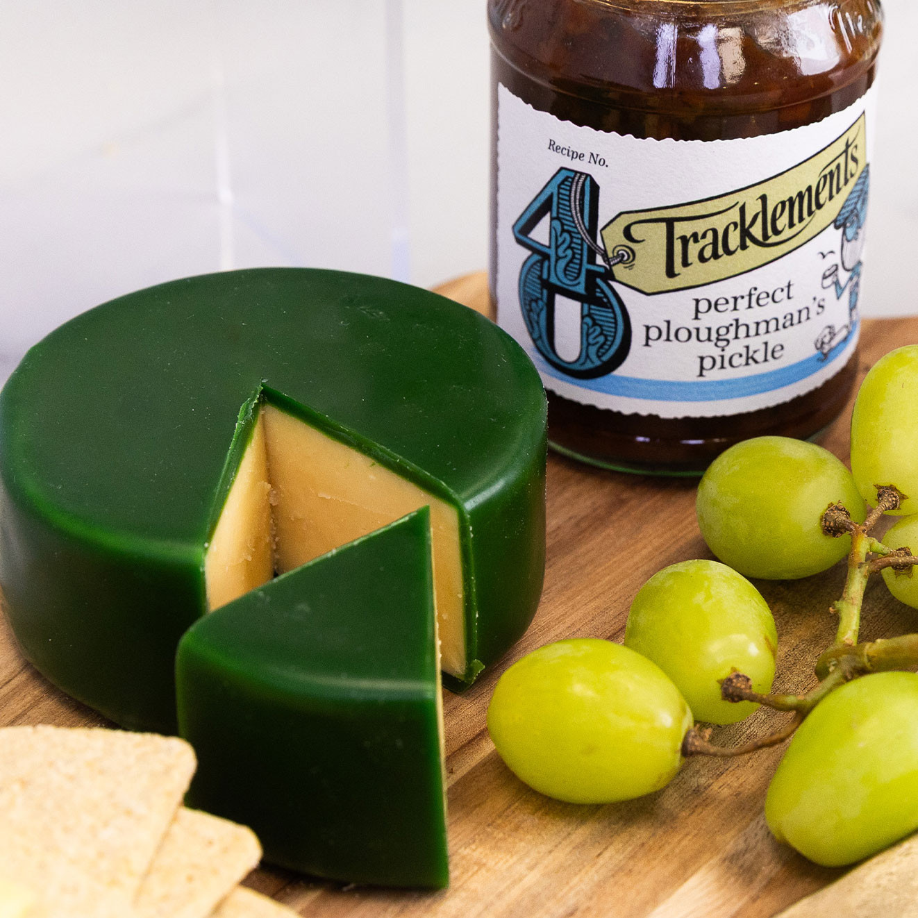 Traditional waxed cheese paired with Tracklements Perfect Ploughman's Pickle, fresh green grapes and artisan crackers for a classic cheeseboard.
