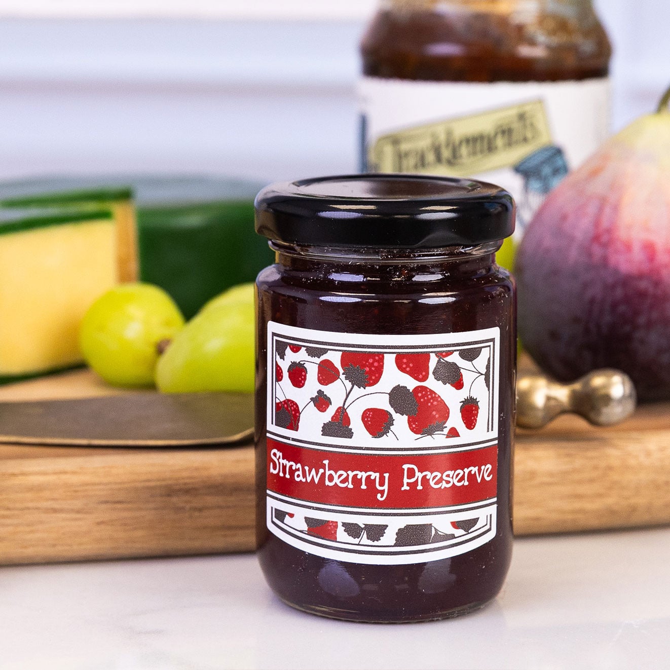 Mini jar of strawberry preserve, ideal for spreading on scones, toast or biscuits as part of a luxury hamper.