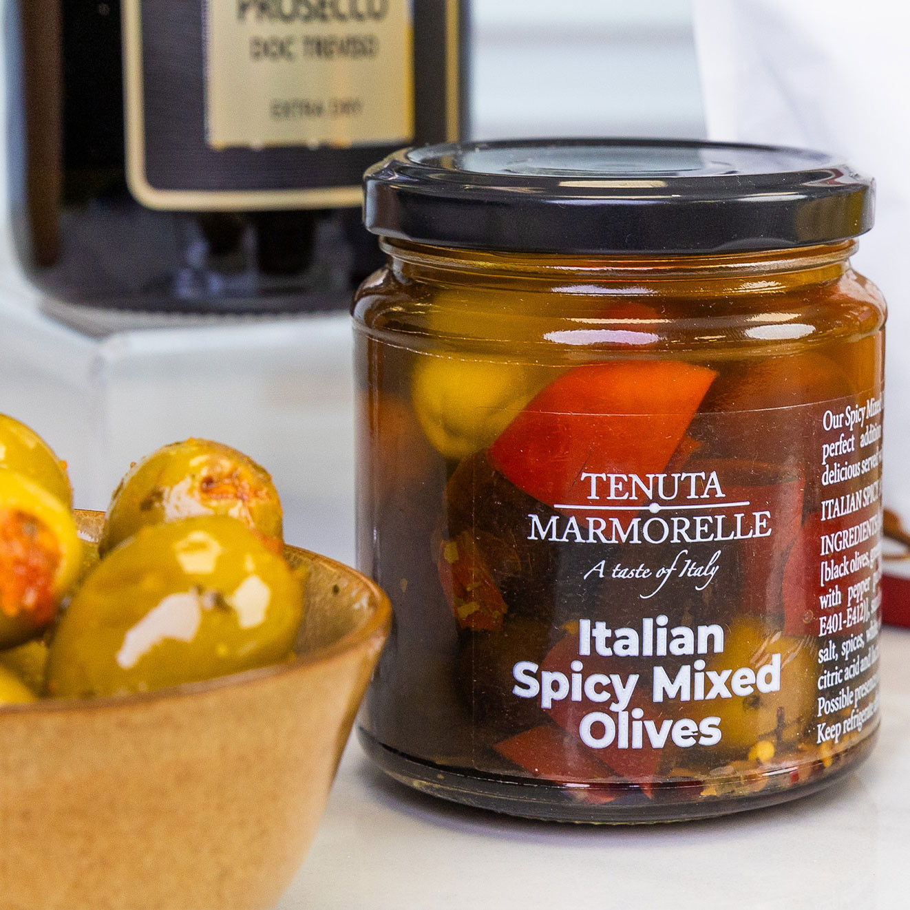 Jar of Tenuta Marmorelle Italian spicy mixed olives served with marinated green olives, perfect for entertaining or sharing.