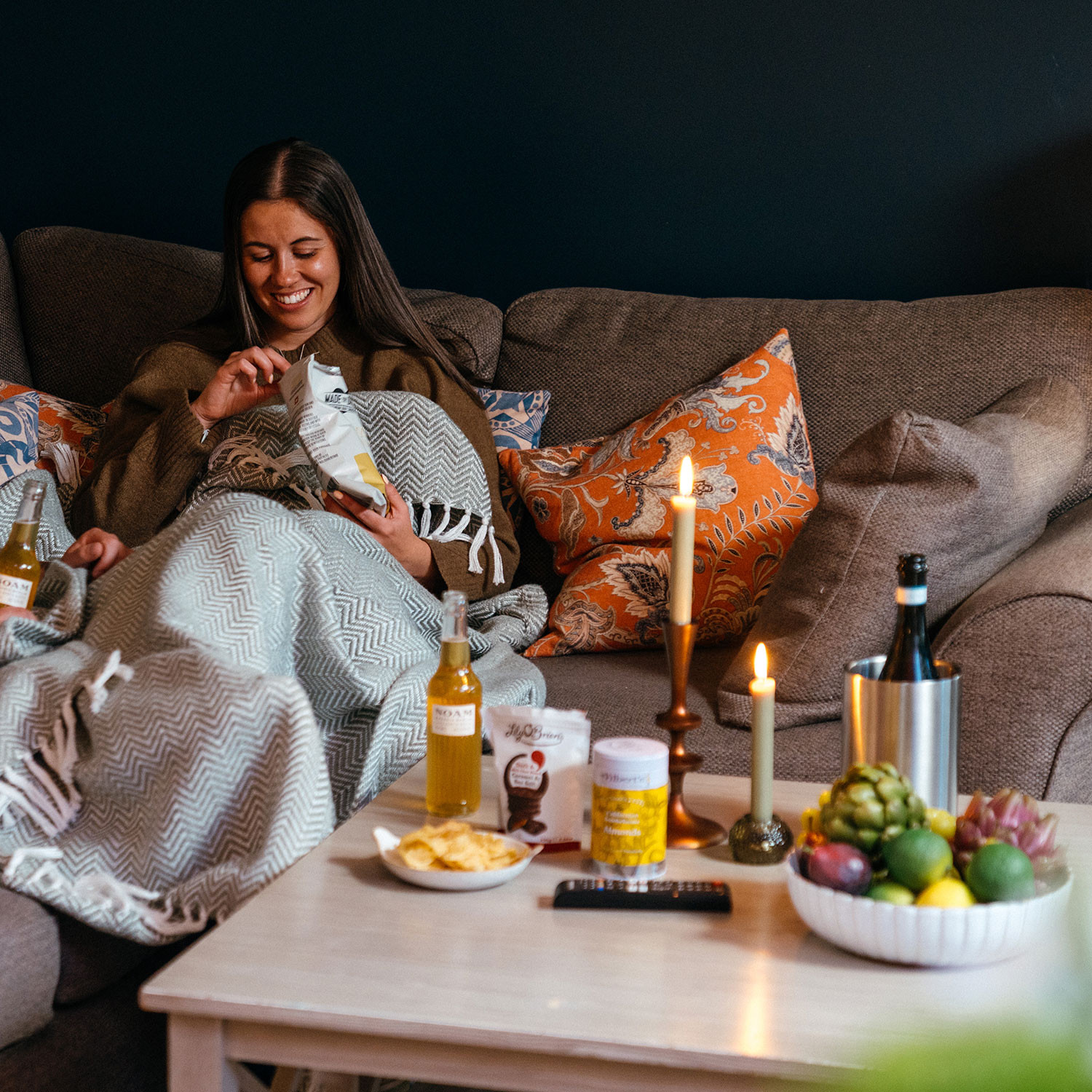Lifestyle shot of Luxury drinks and snacks hamper featuring Prosecco, Bavarian lager, gourmet crisps, olives, smoked almonds, chocolate discs and savoury nibbles.