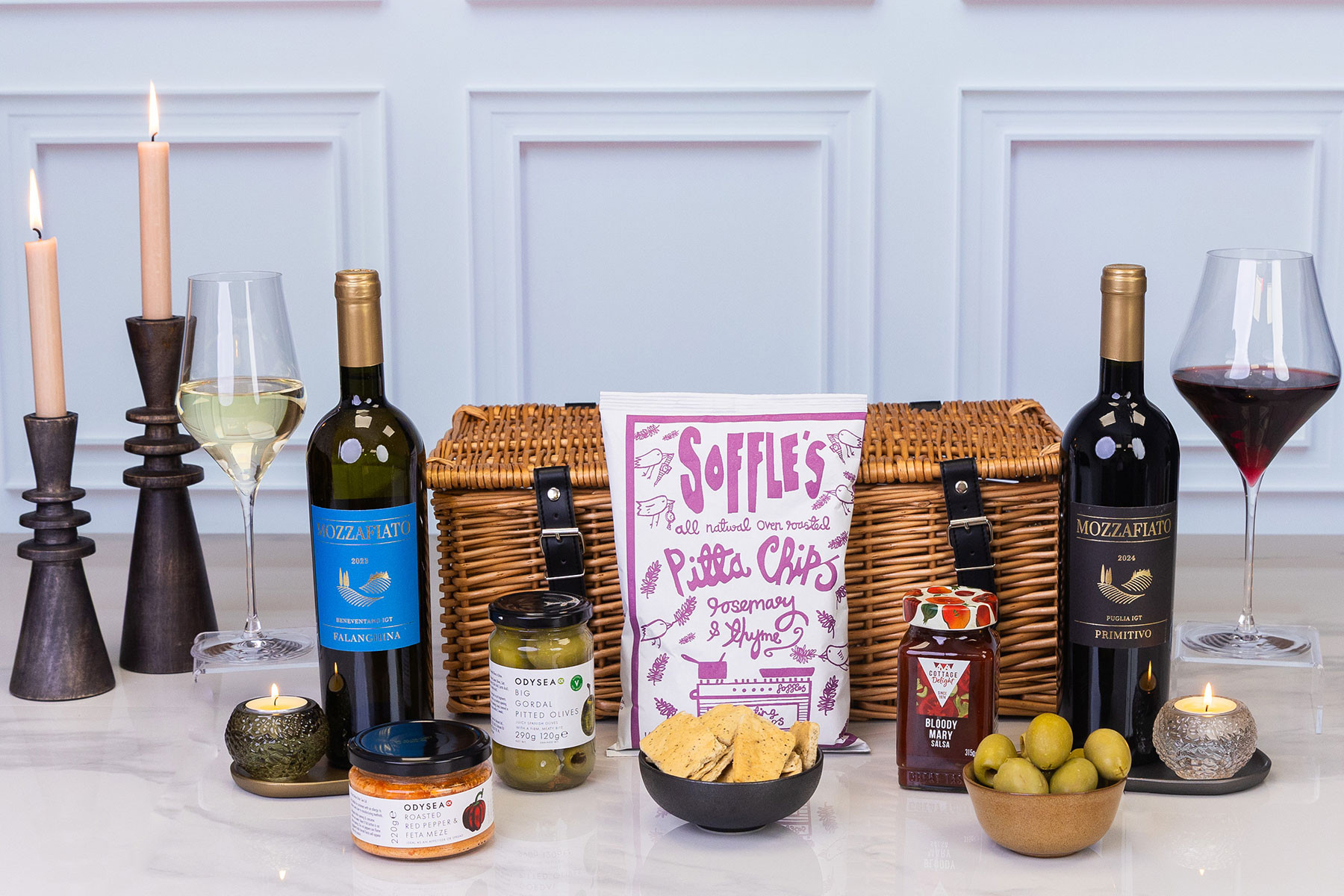 Luxury Italian wine hamper presented in a wicker picnic basket with red and white wines, gourmet snacks, olives, pita chips, salsa and Mediterranean meze.