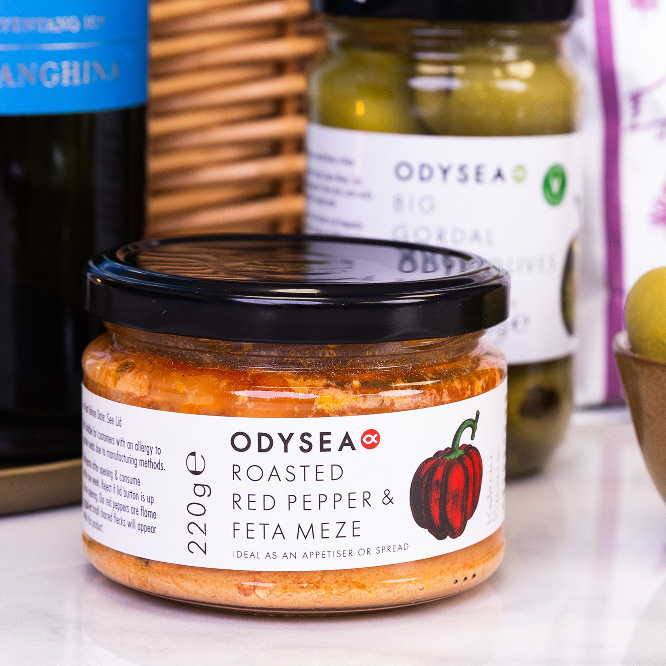 Odysea Roasted Red Pepper & Feta Meze, a Mediterranean-style dip ideal for serving with pita chips and olives.