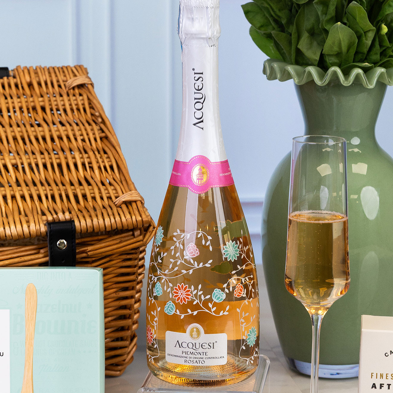 Bottle of Acquesi Piemonte Rosato sparkling wine served with a filled champagne flute, adding a celebratory touch to the hamper.
