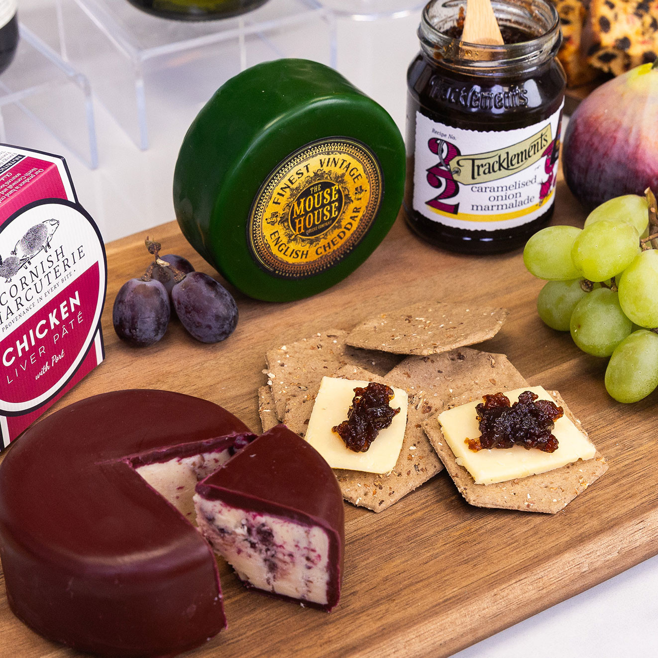 The Mouse House Finest Vintage English Cheddar alongside artisan crackers topped with cheese and caramelised onion marmalade, served with fresh grapes.