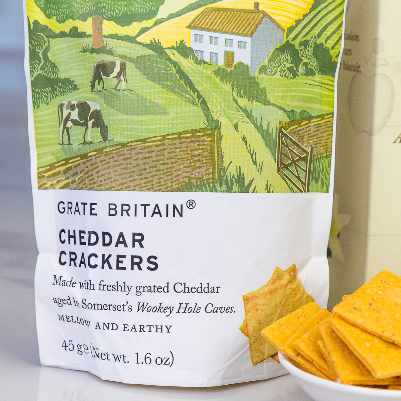 Grate Britain Cheddar Crackers made with Somerset cheddar, displayed beside a bowl of crisp savoury crackers.