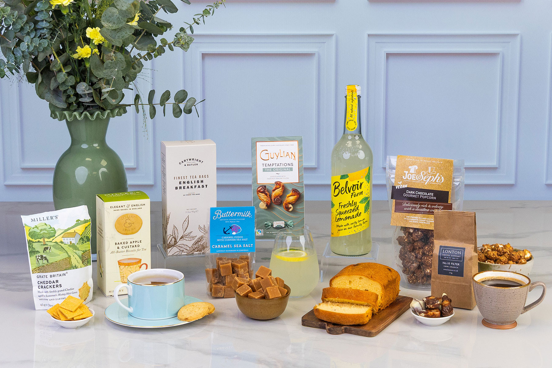 Premium afternoon tea gift hamper featuring artisan biscuits, English breakfast tea, caramel sea salt fudge, lemonade, lemon loaf cake, gourmet popcorn, coffee, chocolates and savoury cheddar crackers, beautifully arranged with fresh flowers.