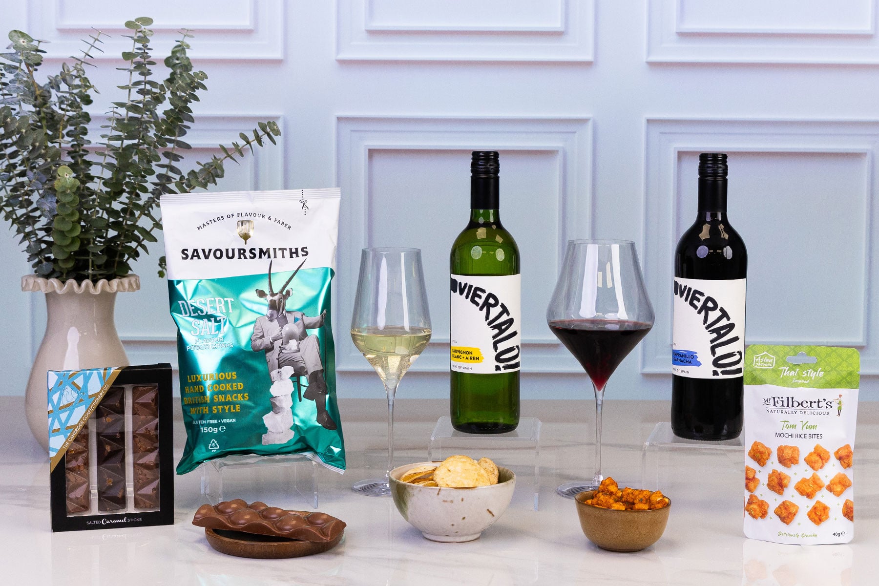 Luxury wine and savoury gift hamper featuring Spanish red and white wines, hand-cooked crisps, salted caramel chocolate, Thai-style mochi rice bites and premium snacks, elegantly presented for sharing.