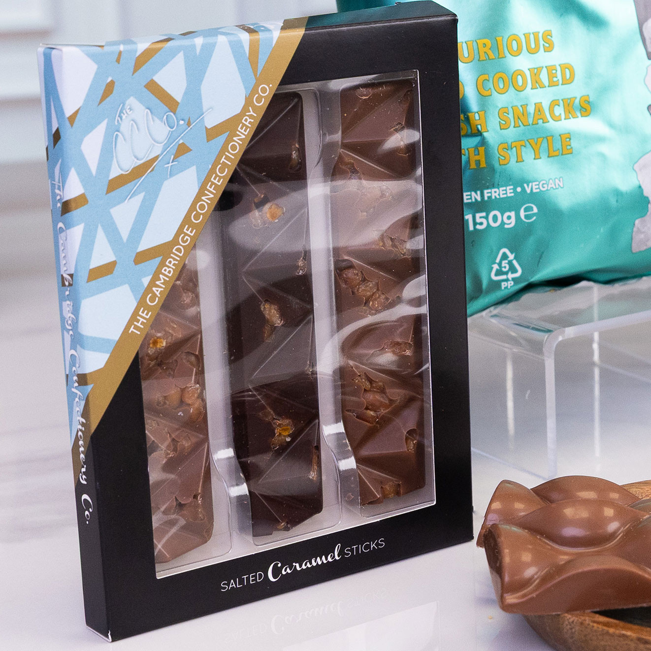 The Cambridge Confectionery Co. Salted Caramel Sticks milk chocolate presented in a gift box with chocolate pieces alongside.