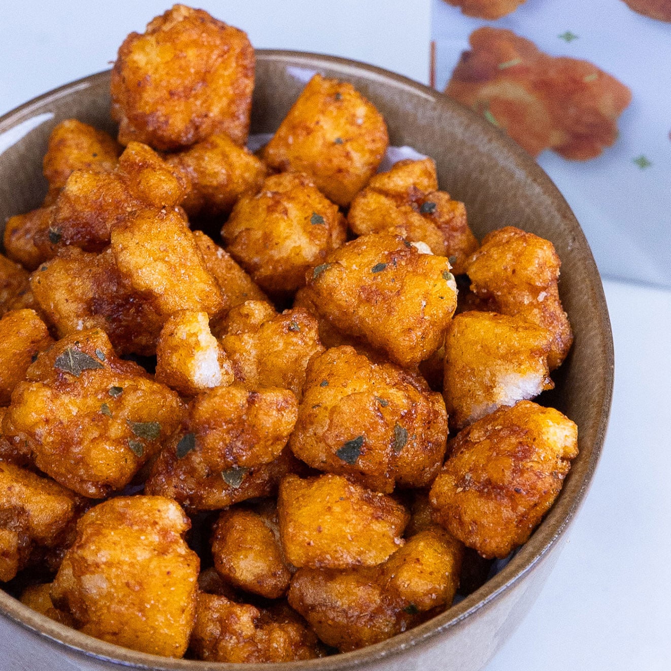 Bowl of crunchy Thai-style Tom Yum mochi rice bites with bold seasoning, offering a spicy and savoury snack.