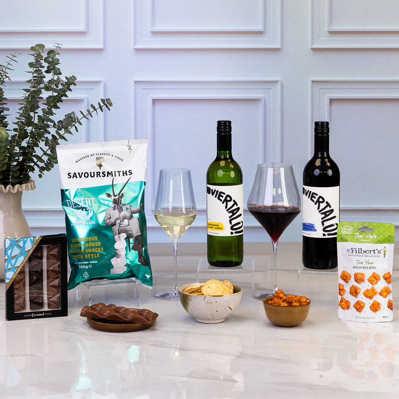 Square shot of the luxury wine and savoury gift hamper featuring Spanish red and white wines, hand-cooked crisps, salted caramel chocolate, Thai-style mochi rice bites and premium snacks, elegantly presented for sharing.