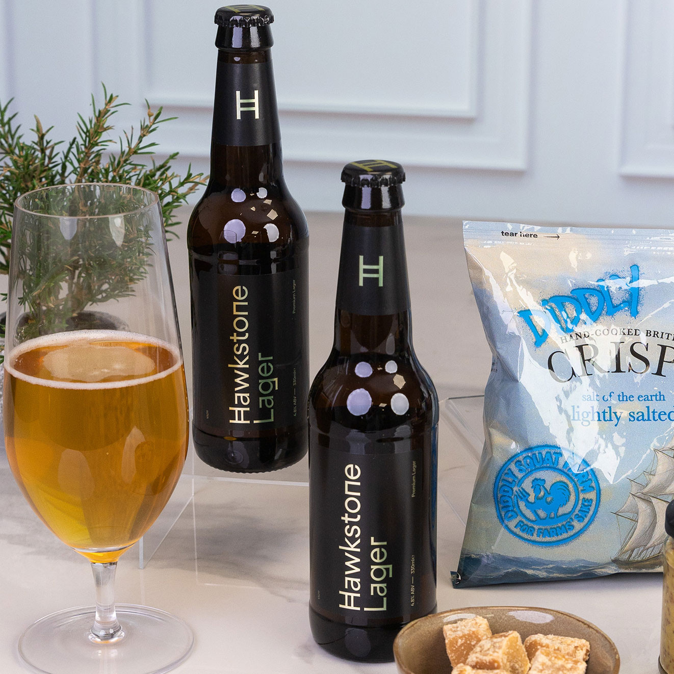 Two bottles of Hawkstone Premium Lager served with a glass of golden lager, highlighting a crisp British craft beer perfect for gifting.