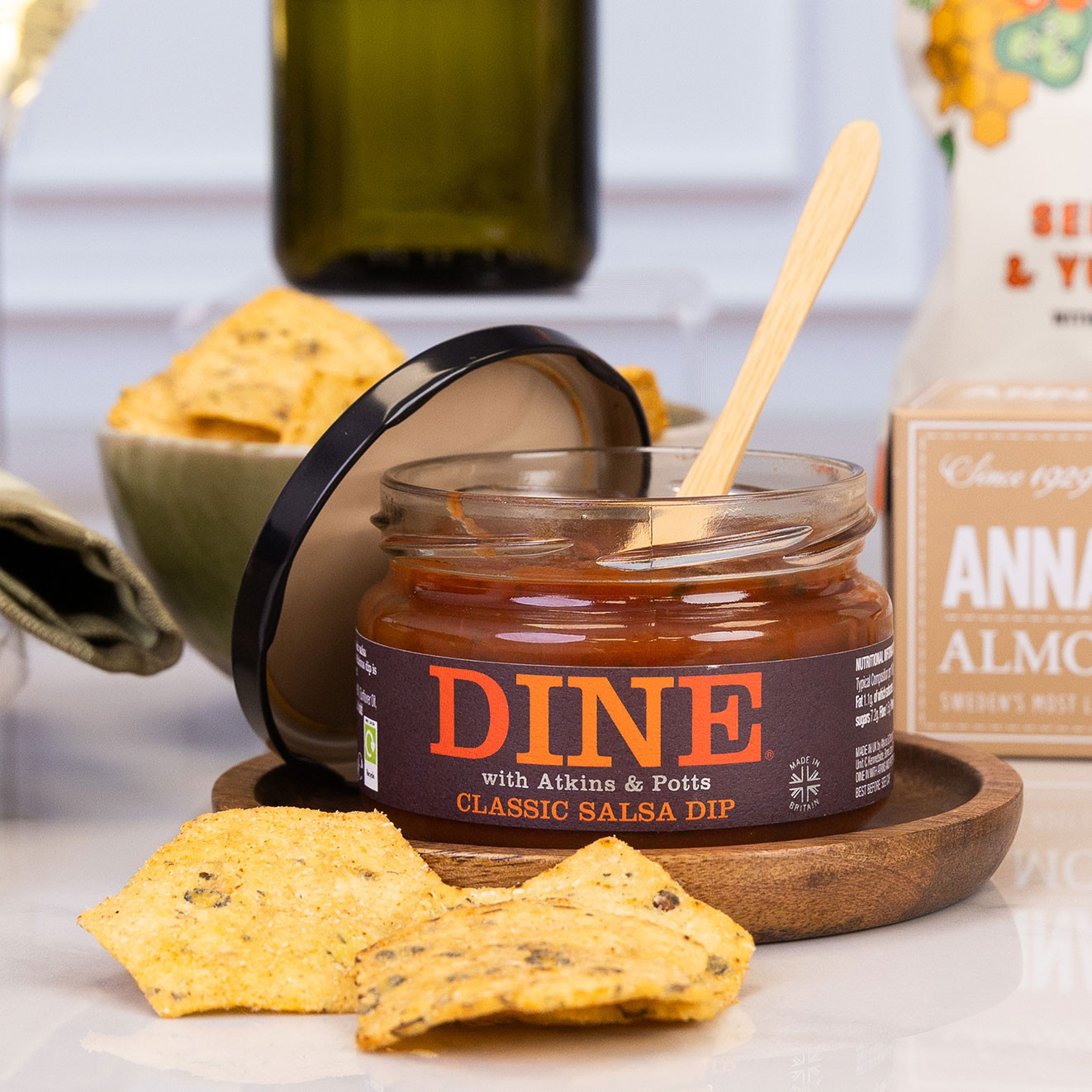 Open jar of DINE Classic Salsa Dip served with seasoned tortilla chips, creating a ready-to-share savoury snack for dipping.