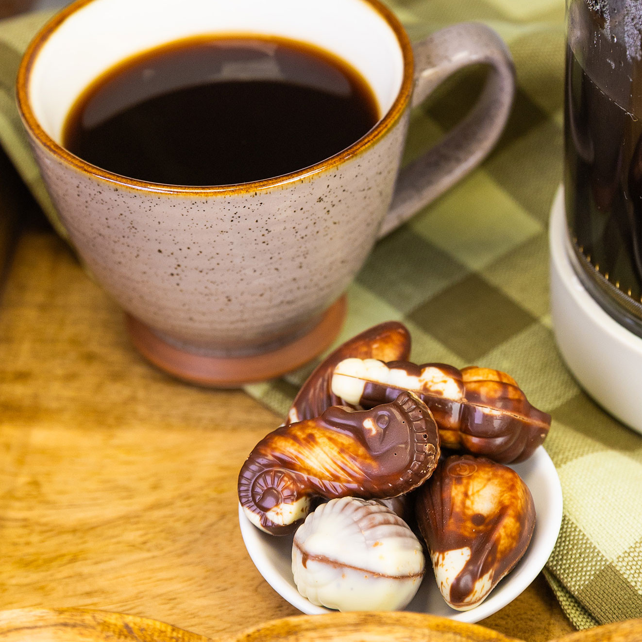 Selection of Guylian Belgian seashell chocolates served beside a freshly brewed cup of black coffee, creating a classic coffee and chocolate pairing.