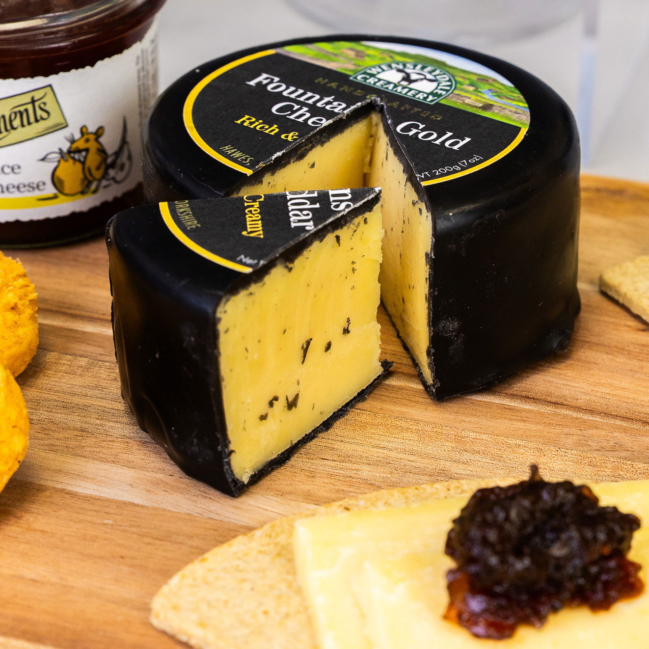 Wheel of Fountain's Gold mature cheddar with a wedge cut out, served with crackers and rich chutney for a traditional cheeseboard experience.