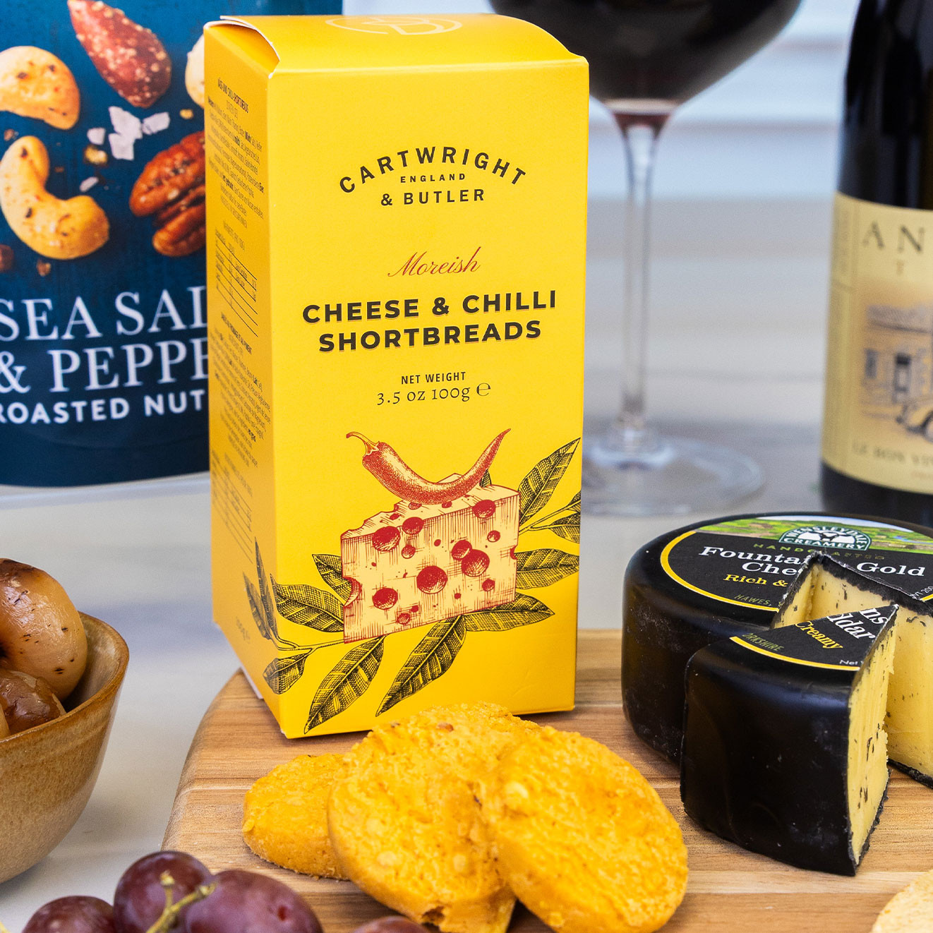 Cartwright & Butler cheese and chilli shortbread biscuits, crisp and savoury, displayed alongside mature cheddar and a glass of red wine.