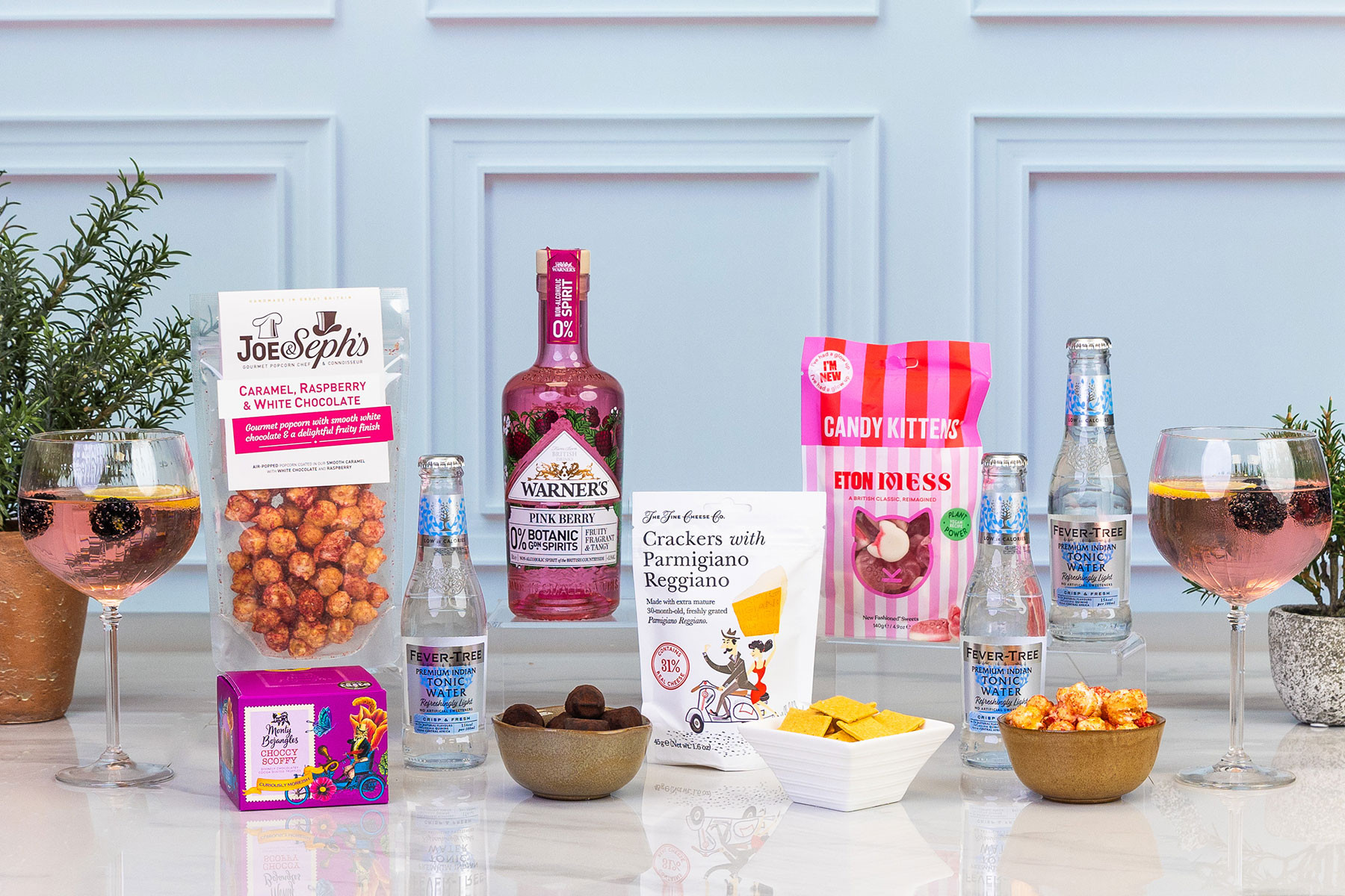 Premium alcohol-free pink gin gift set featuring Warner's Pink Berry 0% botanical spirit, Fever-Tree light tonic water, gourmet snacks and sweet treats, styled for an elegant alcohol-free celebration.