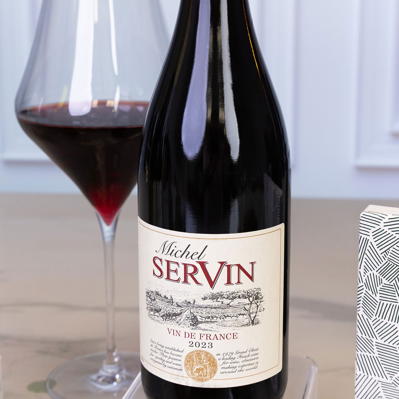 Bottle of Michel Servin Vin de France 2023 served with a glass of red wine, offering a smooth French red ideal for pairing with cheese and pâté.